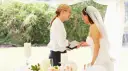 Panna młoda z welonem i wedding plannerka dyskutują przy stole. Czy warto wynająć wedding plannera, czy poradzić sobie samemu?