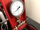 Manometr do prób szczelności gazu, z tarczą wskazującą ciśnienie w MPa. Urządzenie jest częścią czerwonej skrzynki narzędziowej.
