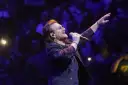 Bono z U2 śpiewa na koncercie, zapowiadając u2 nowa płyta. Tłum w ciemnościach reaguje na jego występ.