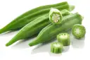 Kilka zielonych strąków okry, w tym przekrojone, ukazujące nasiona. Okra po polsku to pyszny dodatek do dań.