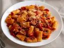 Pyszny makaron z sosem pomidorowym, grzybami i parmezanem na białym talerzu.