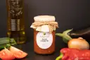 Słoik z warzywnym pesto z oliwą z oliwek, otoczony świeżymi warzywami. To pyszne pesto z pewnością wzbogaci każde danie.