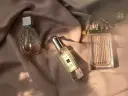 Drei Parfümflaschen auf rosafarbenem Stoff, im Sonnenlicht.