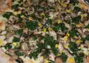 Pyszna pizza ze szpinakiem, grzybami i kukurydzą, obficie posypana serem.