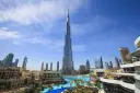 Burj Khalifa, najwyższy budynek świata, na tle błękitnego nieba z chmurami, otoczony nowoczesnymi budynkami i basenem.