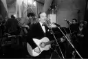 Zbigniew Kurtycz z gitarą i zespołem wykonuje swoje utwory. Wokalista w czarnym aksamitnym fraku śpiewa do mikrofonu.