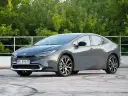 Szary Toyota Prius hybryda na tle zieleni. Zastanawiasz się, ile pali Toyota Prius hybryda? Ten model zachwyca niskim spalaniem.