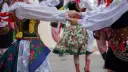 Tancerze w barwnych strojach ludowych, żywa muzyka folkowa w tle.
