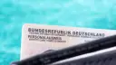 Niemiecki dowód osobisty (Personalausweis) na tle turkusowym.