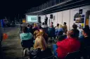 Prezentacja na targach budowlanych. Mężczyzna przemawia do zgromadzonej publiczności, która siedzi na krzesłach.