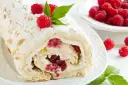 Rolada bezowa z mascarpone i malinami, posypana cukrem pudrem i płatkami migdałów.