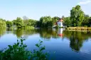 Malowniczy kościół na wodzie w Zwierzyńcu, otoczony zielenią i odbijający się w spokojnej tafli jeziora.