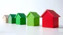 Rząd domków: beżowy, zielony, zielony, zielony, czerwony. Symbolizują różne poziomy klasy energetycznej.