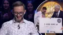 Marek Wojtun wygrał milion w Milionerach! Uśmiechnięty uczestnik odbiera czek z nagrodą.