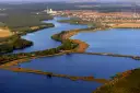 Widok z lotu ptaka na jezioro z wyspami, lasami i zabudowaniami w tle.
