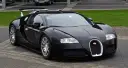 Czarny Bugatti Veyron z dużym tylnym spojlerem zaparkowany na bruku.