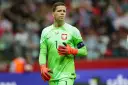 Wojciech Szczęsny, bramkarz reprezentacji Polski, w zielonej koszulce i pomarańczowych rękawicach. Jego imponujący wzrost pozwala mu skutecznie bronić.