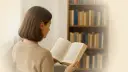 Junge Frau liest ein Buch vor einem Bücherregal.