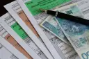 Formularze PIT, długopis i polskie banknoty. Miesięczna kwota wolna od podatku jest ważnym elementem rozliczeń.