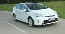 Biała Toyota Prius w ruchu. Czy warto kupić ten hybrydowy samochód?