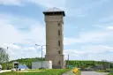 Wieża widokowa w Suszynie, zbudowana z jasnego kamienia, góruje nad zielonymi wzgórzami.