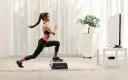 Kobieta wykonuje wykroki na stopniu, ćwicząc w domu. To świetny przykład, jak zacząć trening interwałowy co to jest i jak go stosować.