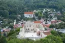 Ruiny zamku w Kazimierzu Dolnym na tle zielonych wzgórz i zabudowań.