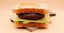 Burger z wołowiny, serem, sałatą i tostami na desce.