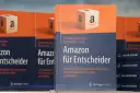 Bücher "Amazon für Entscheider" mit Amazon-Logo-Würfel im Vordergrund.