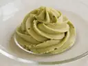 Puszysty krem pistacjowy do tortu, udekorowany na talerzyku.