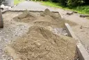 Kopce piasku czekają na ułożenie kostki brukowej. Trudno oszacować, ile piasku na m2 kostki, ale materiału jest sporo.