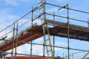 Rusztowanie aluminiowe z drabiną na tle błękitnego nieba.