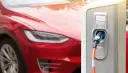 Czerwona Tesla podłączona do ładowarki elektrycznej.