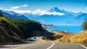 Malownicza droga w Nowej Zelandii prowadzi do turkusowego jeziora i ośnieżonych gór. Idealna temperatura na zwiedzanie.