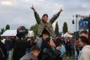 Dziewczyna na ramionach chłopaka cieszy się na Juwenaliach Politechniki Lubelskiej. W tle scena i tłum bawiących się studentów.