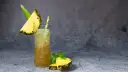 Klasyczny Mai Tai z sokami, ozdobiony kawałkiem ananasa i miętą. Idealny na tropikalny wieczór.