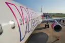 Samolot Wizz Air z pasażerami wsiadającymi po schodkach na lotnisku.