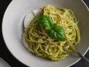 Makaron spaghetti z pesto i mozzarellą, ozdobiony listkiem bazylii. Idealny makaron na diecie, lekki i pełen smaku.