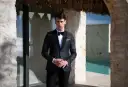 Elegancki mężczyzna w smokingu, idealny przykład stroju black tie na wesele. Różnica między ubiorem black tie a cocktail dress dla gości weselnych jest widoczna.
