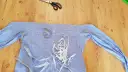 Przygotowania do przeróbki koszuli, by zmniejszyć bluzkę w ramionach. Nożyczki, miarka i szpilki czekają na pracę.