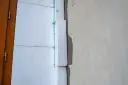 Izolacja styropianowa przy drzwiach, z pianką i narożnikami do elewacji.