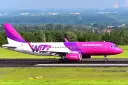 Różowy samolot Wizz Air na pasie startowym.
