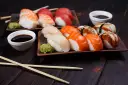 Wyśmienite japońskie sushi: nigiri z łososiem, rybą maślaną i krewetką, podane z wasabi i sosem sojowym.