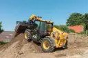 Żółty ładowarka teleskopowa JCB 525-60 z podniesionym wysięgnikiem i łyżką, pracująca na budowie.