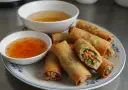 Chrupiące spring rolls z warzywnym farszem, podane z dwoma sosami. Idealne na przekąskę.