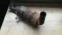 Zardzewiały, zużyty filtr DPF na drewnianym blacie.