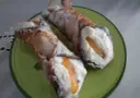 Dwa pyszne cannoli z kremem i kandyzowaną skórką pomarańczową, posypane cukrem pudrem. Ten makaron to prawdziwa rozkosz!