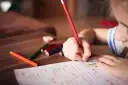 Dziecko zmagające się z dysleksją, dysgrafią, dysortografią i dyskalkulią pisze kredkami.