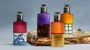 Vier bunte Parfumflaschen mit silbernen Verschlüssen auf goldenem Untergrund.