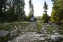 Kamper w górskiej scenerii Szwajcarii, na kamienistej drodze wśród świerków.